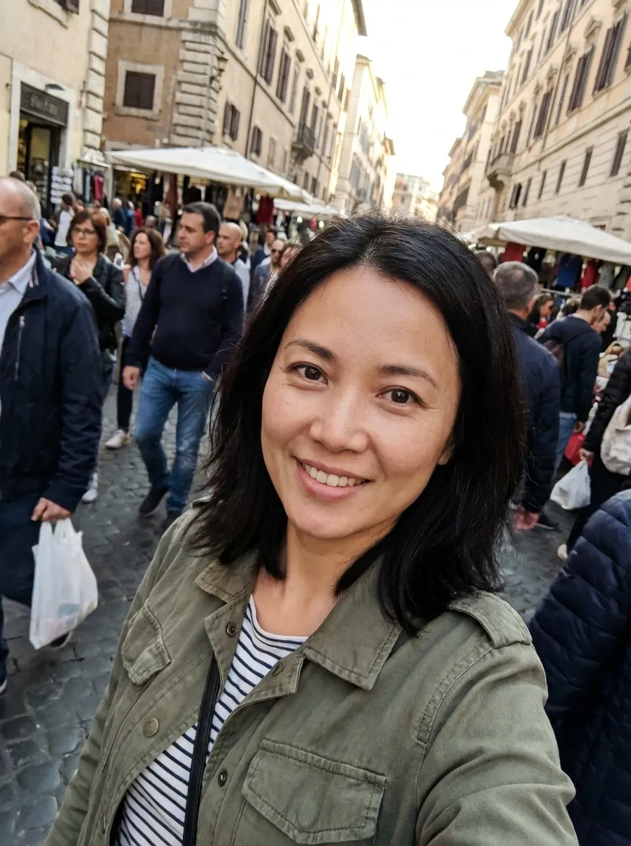 Travel selfie of a woman in an olive jacket and striped top on a busy European street